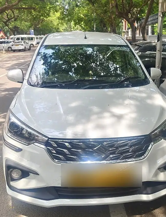 The front of one of our white Maruti Ertiga Tour M cars, parked under trees